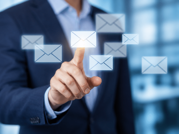 Business professional pointing at floating email icons on a digital interface.