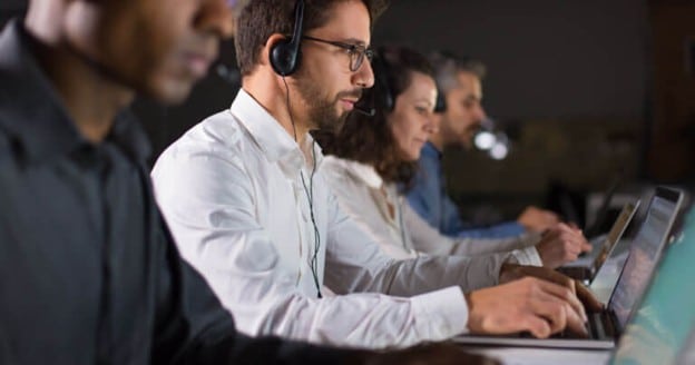 IT support team working on laptops while assisting business clients.